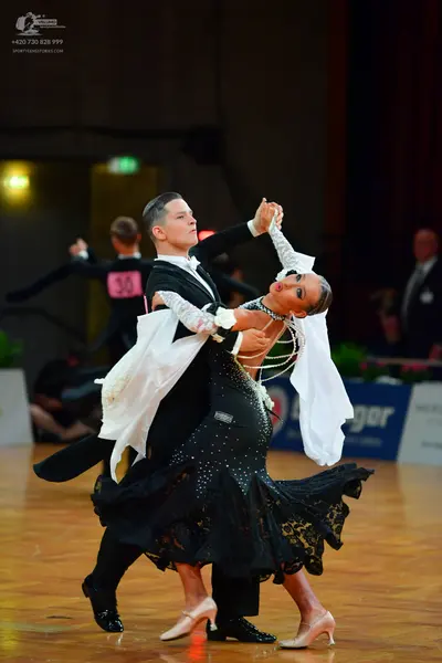 Dancesport competitor: Male dancer: black ballroom tailcoat with white ruffled cuffs and black trousers