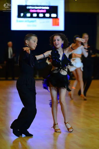 Dancesport competitor: Male dancer in foreground: black long-sleeved shirt and black trousers
