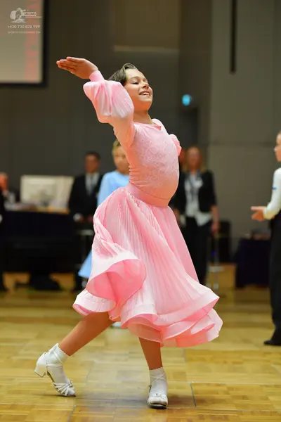 Dancesport competitor: Female dancer: pink ballroom gown with a voluminous, ruffled skirt and long slee