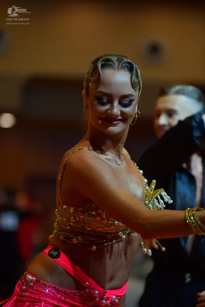 Dancesport competitor: Female dancer: pink sequined latin dress with pearl and bead embellishments, gol