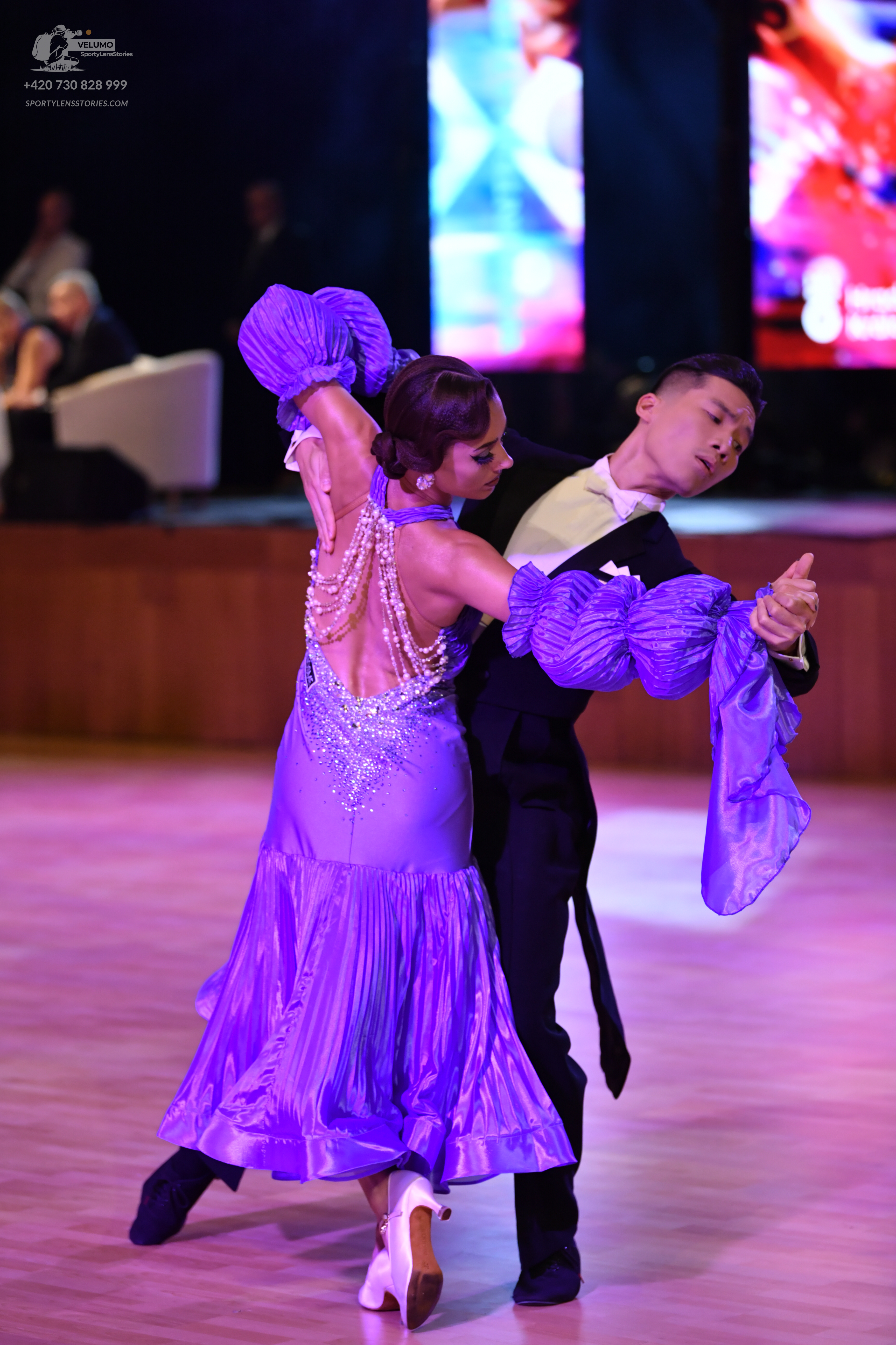 Dancesport competitor: Female dancer: purple satin ballroom dress with a pleated skirt, voluminous ruff