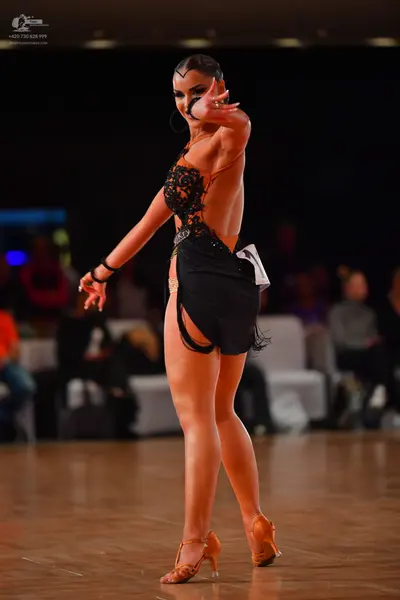 Dancesport competitor: Female dancer: black Latin dress with an intricate black lace bodice and a short
