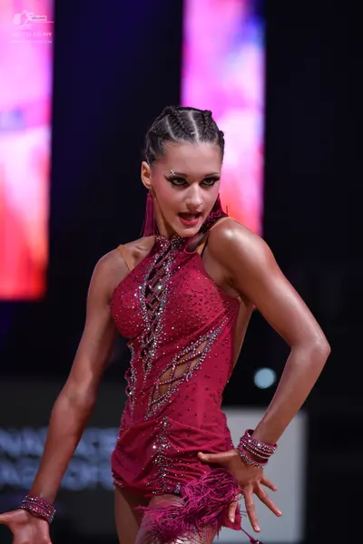 Dancesport competitor: Female dancer: magenta latin dress with sequins, mesh panels, a lace-up bodice, 