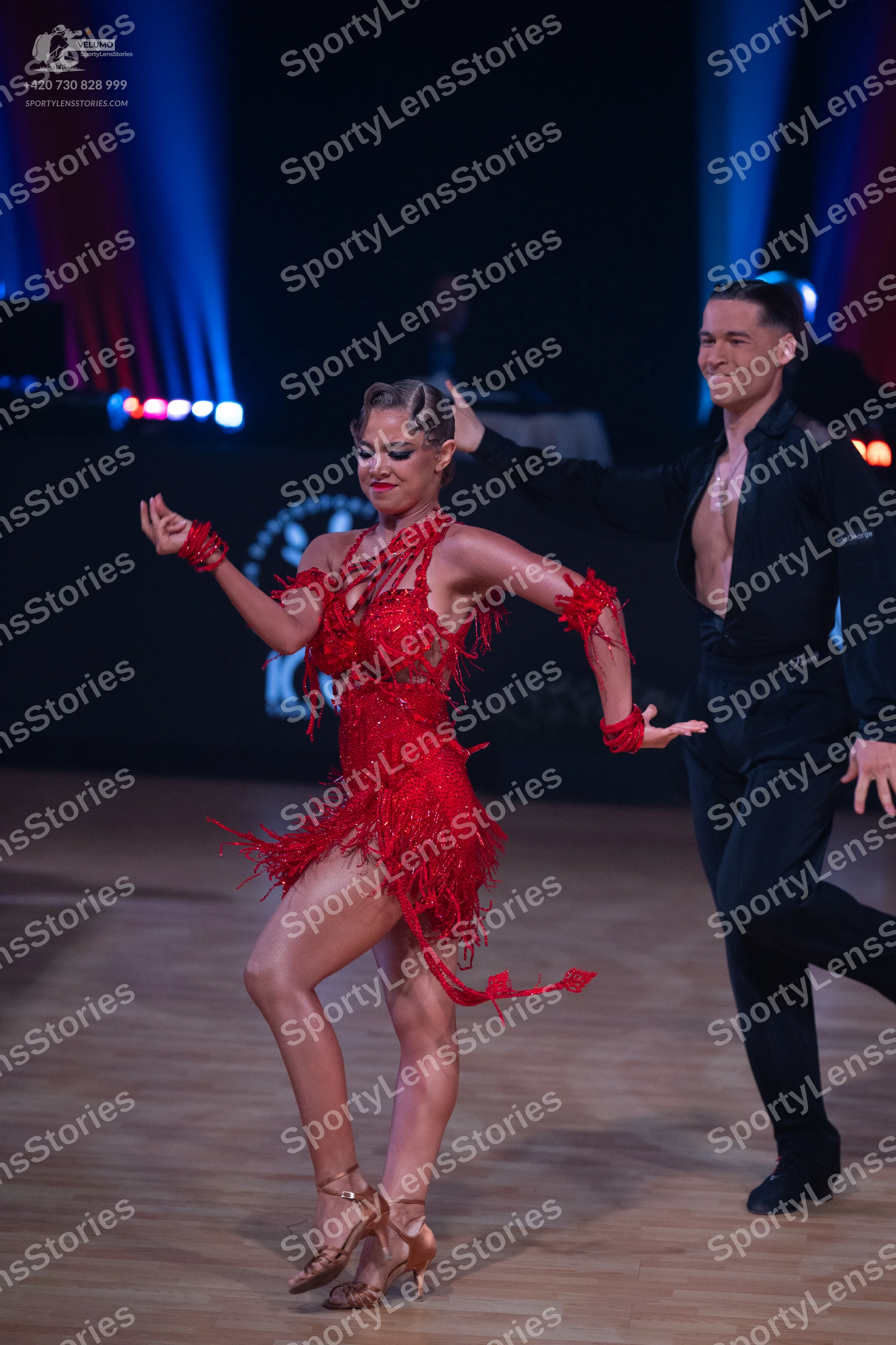Dancesport competitor: Female dancer: red Latin dress with fringe and matching red wristbands