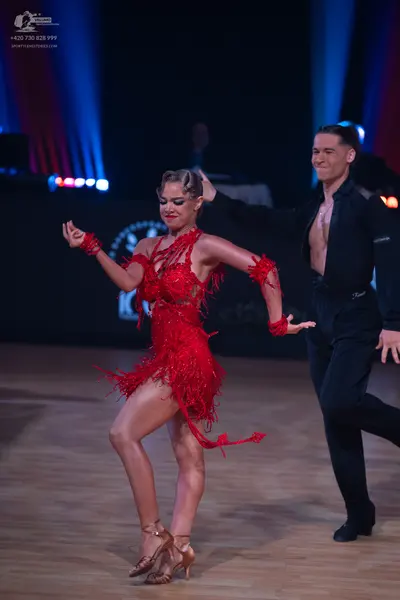 Dancesport competitor: Female dancer: red Latin dress with fringe and matching red wristbands