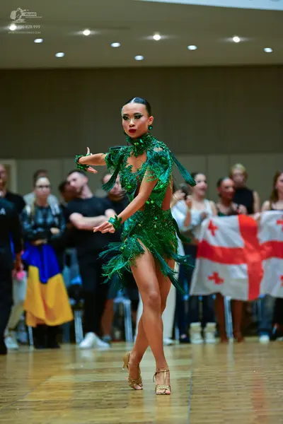 Dancesport competitor: Female dancer: emerald green latin dance dress with sequins and feather-like fri