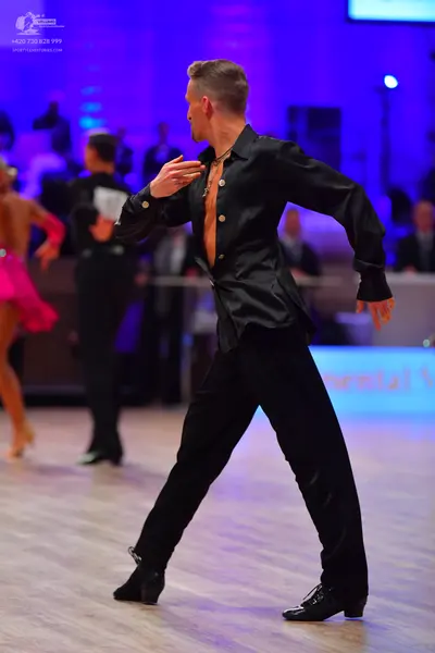 Dancesport competitor: Male dancer: black satin long-sleeved shirt, black trousers, black dance shoes, 