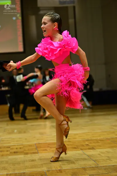 Dancesport competitor: Female dancer: bright pink Latin dress with large ruffles on the bodice and a fe