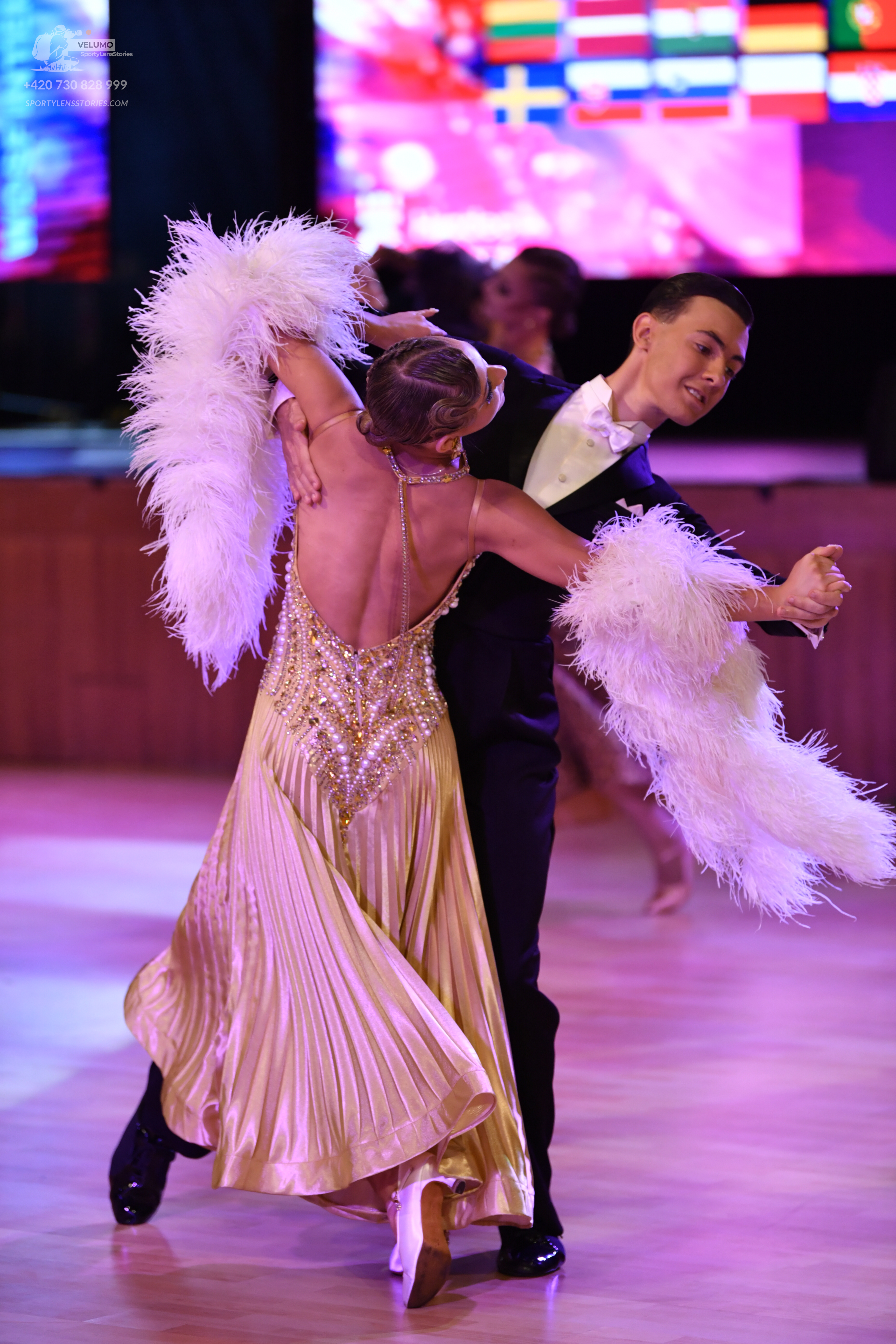 Dancesport competitor: Female dancer: gold, pleated, satin-like ballgown with intricate beadwork/sequin