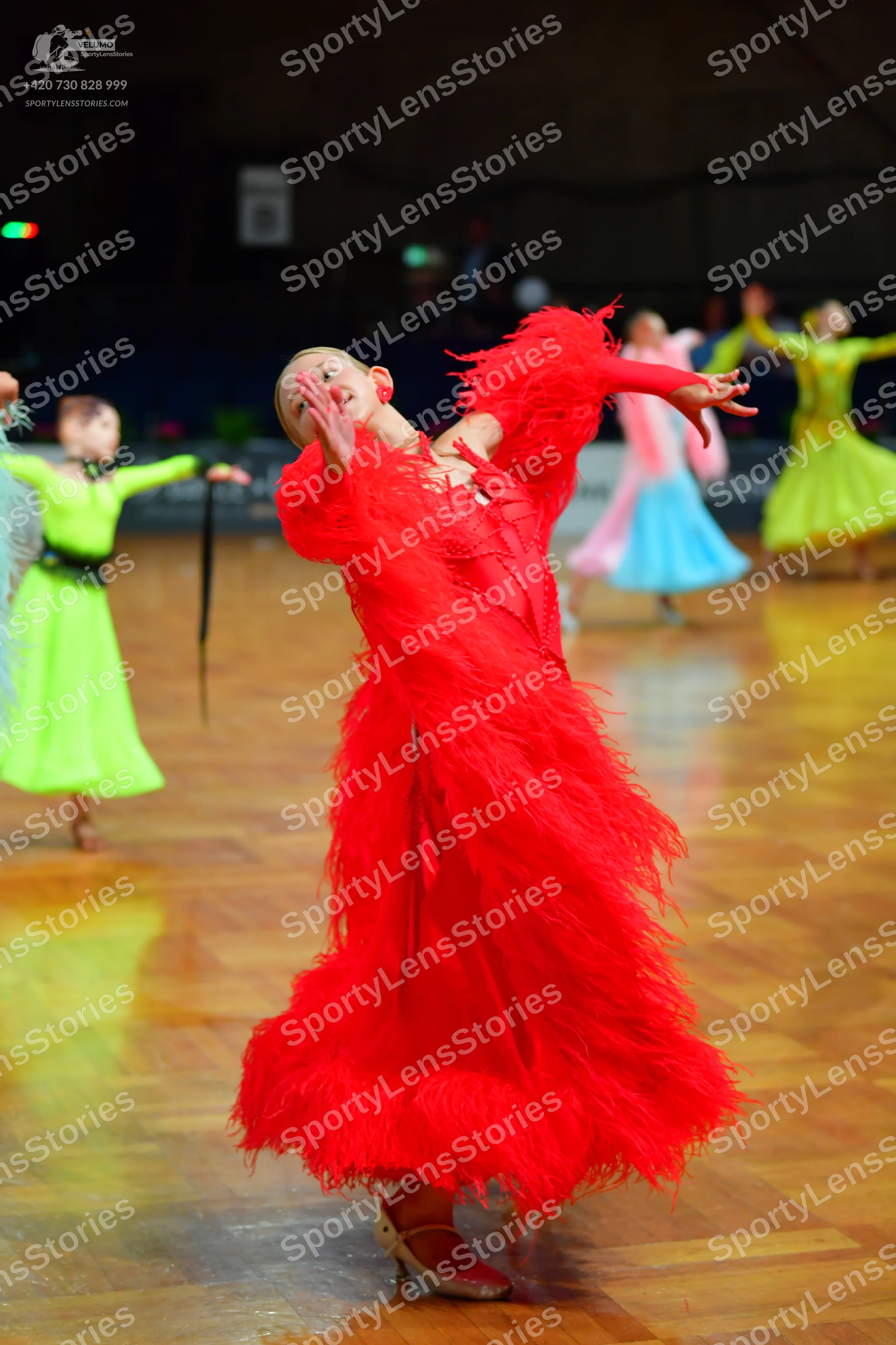Dancesport competitor: Female dancer in foreground: red latin dress with long, voluminous fringe