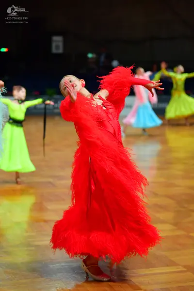 Dancesport competitor: Female dancer in foreground: red latin dress with long, voluminous fringe