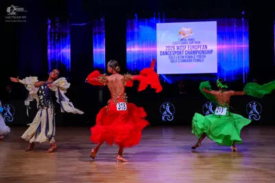 Dancesport competitor: First dancer: white and dark blue latin dress with flowing, layered fabric