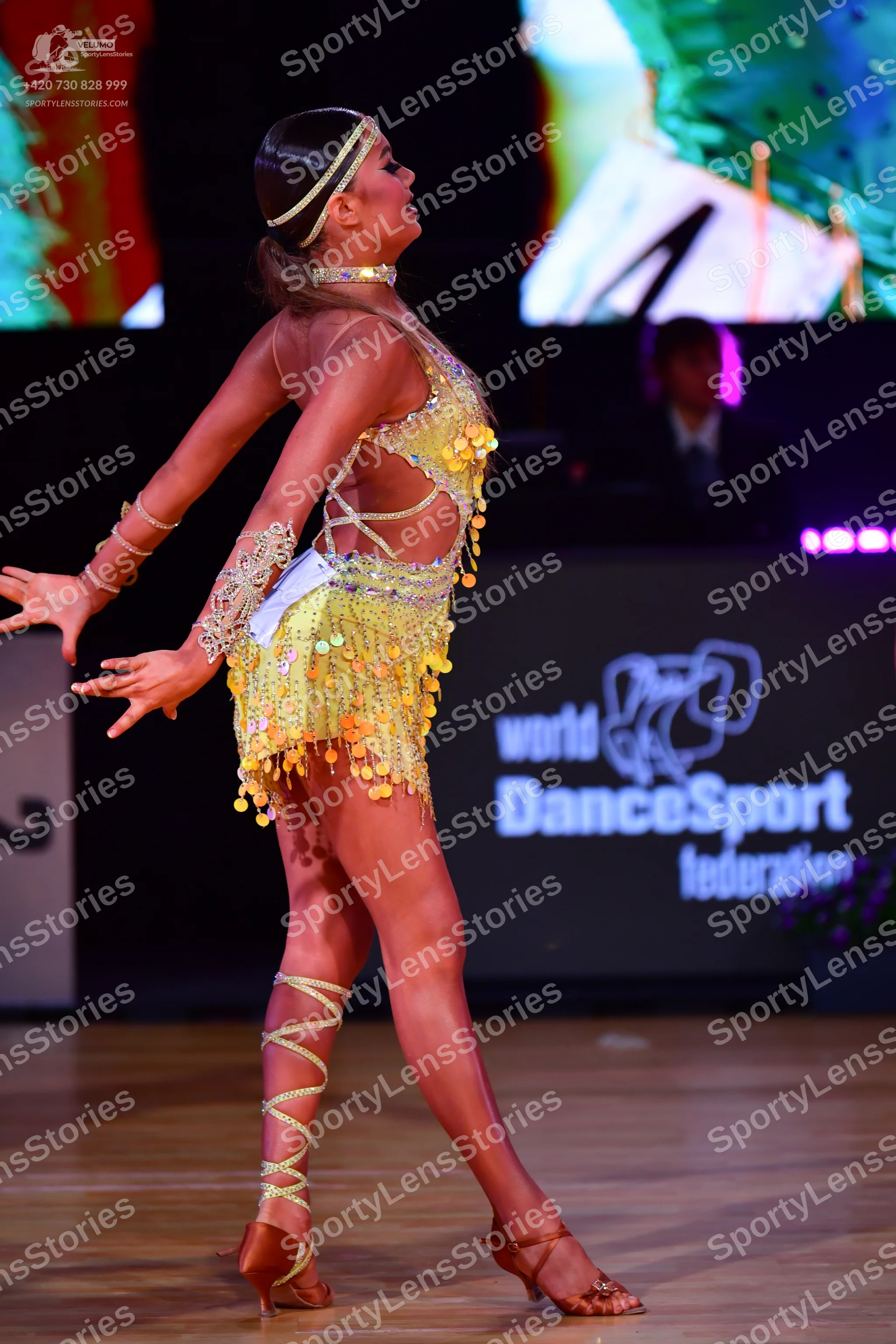 Dancesport competitor: Female dancer: gold/yellow latin dance costume featuring sequins, cutouts, and g