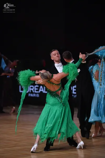 Dancesport competitor: Female dancer (foreground): emerald green dance dress with heavy sequin and crys