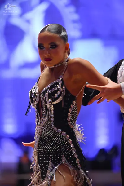 Dancesport competitor: Female dancer: black latin dress decorated with silver sequins, rhinestones, and