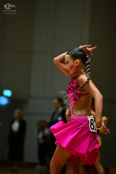 Dancesport competitor: Female dancer: pink latin dress with black polka dots, sequins, and cutouts, pai