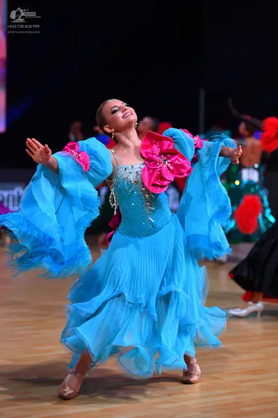 Dancesport competitor: Female dancer: light blue ballroom dress with a sequined bodice, large pink ruff
