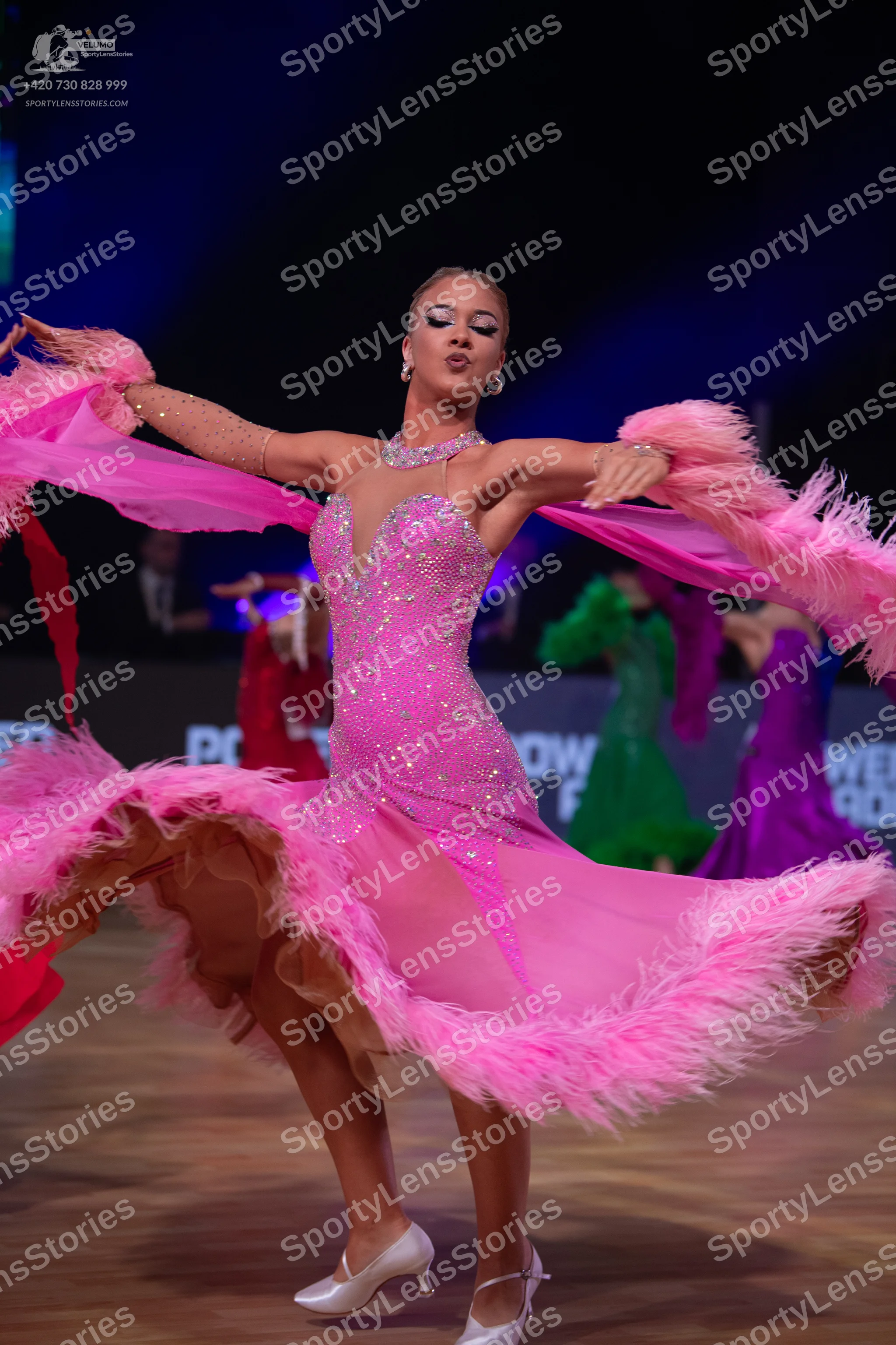Dancesport competitor: Female dancer in foreground: pink latin dance dress with a sequined bodice, shee