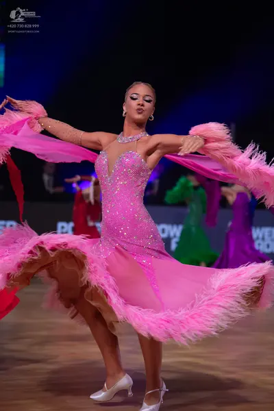Dancesport competitor: Female dancer in foreground: pink latin dance dress with a sequined bodice, shee