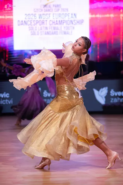 Dancesport competitor: Female dancer: gold latin dress with a shimmering, multi-layered, ruffled skirt,