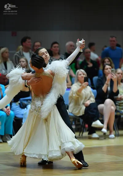 Dancesport competitor: Female dancer: cream-colored ballroom gown with large white feathery trim on the