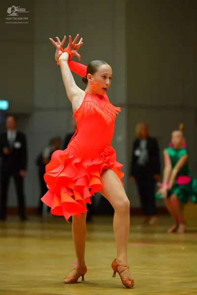 Dancesport competitor: Female dancer: bright coral/neon orange latin dress with fringe on the bodice an