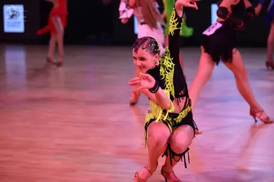 Dancesport competitor: Foreground female dancer: black latin dance costume with neon lime green accents