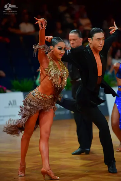 Dancesport competitor: Female dancer: gold Latin dance costume with sequins and long fringe, featuring 