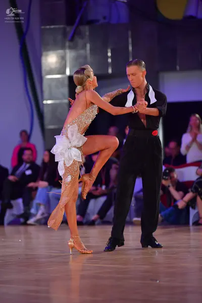 Dancesport competitor: Female dancer: champagne-colored sequined Latin dance dress with a large white f