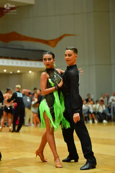 Dancesport competitor: Female dancer: dark green Latin dress with sequins and bright neon green fringe