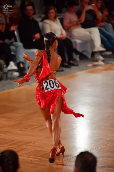 Dancesport competitor #206: Female dancer: red Latin dress with a flowing skirt and red wrist accessories