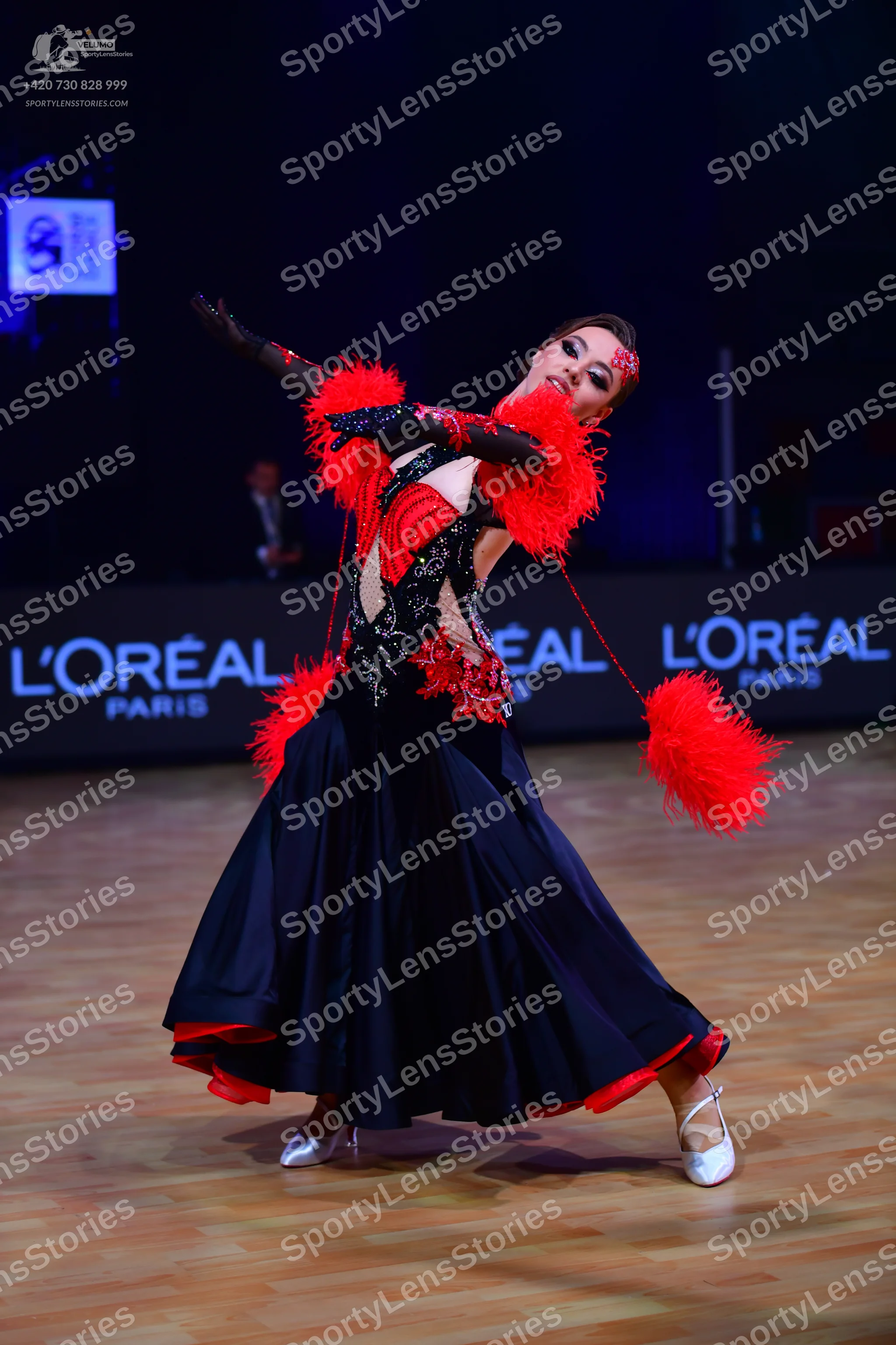 Dancesport competitor: Female dancer: black ballroom dress with red accents, featuring a lace-patterned