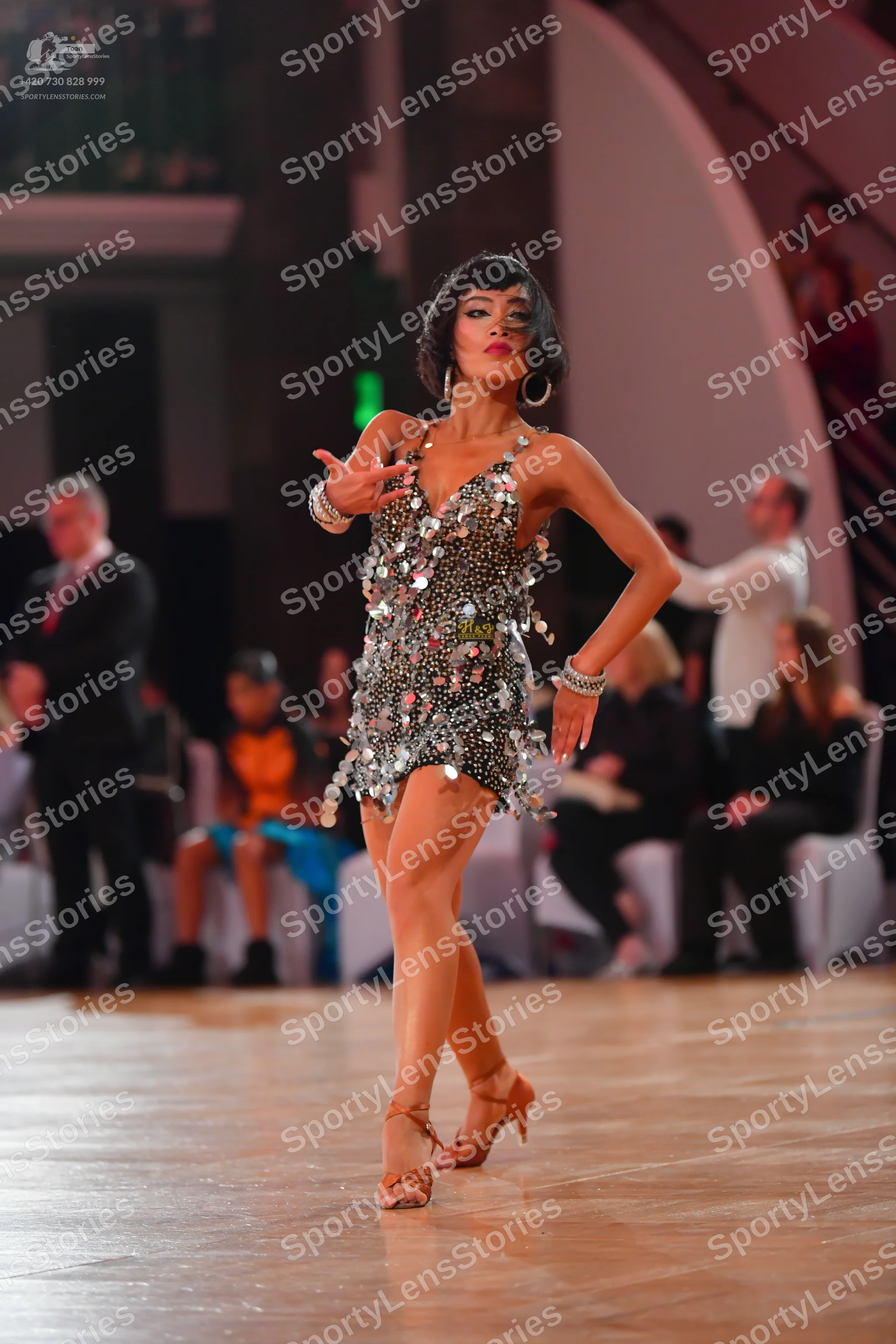 Dancesport competitor: Female dancer: silver sequined latin dress with large hoop earrings and silver b