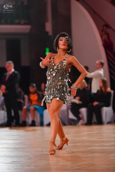 Dancesport competitor: Female dancer: silver sequined latin dress with large hoop earrings and silver b