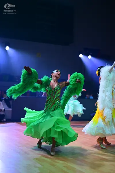 Dancesport competitor: Female dancer in foreground: bright green ballroom dress with a sequined bodice 