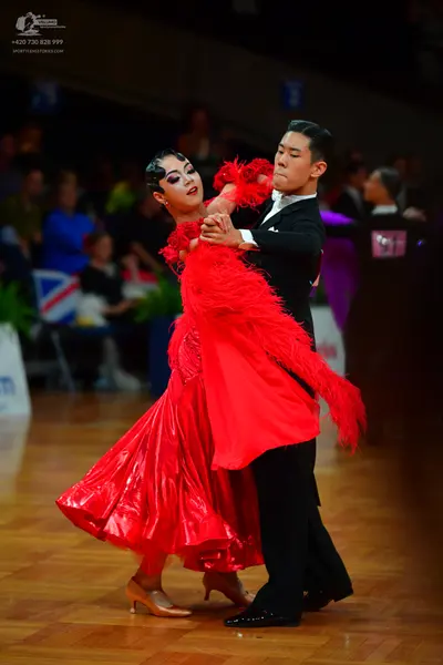 Dancesport competitor: Female dancer: red latin dress with shiny fabric and large red feather accents
