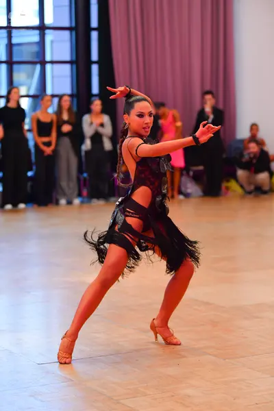 Dancesport competitor: Female dancer: black latin dress with sheer mesh panels and long black fringe
