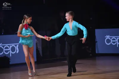 Dancesport competitor: Female dancer: turquoise latin dress with a large pink flower accessory on the s