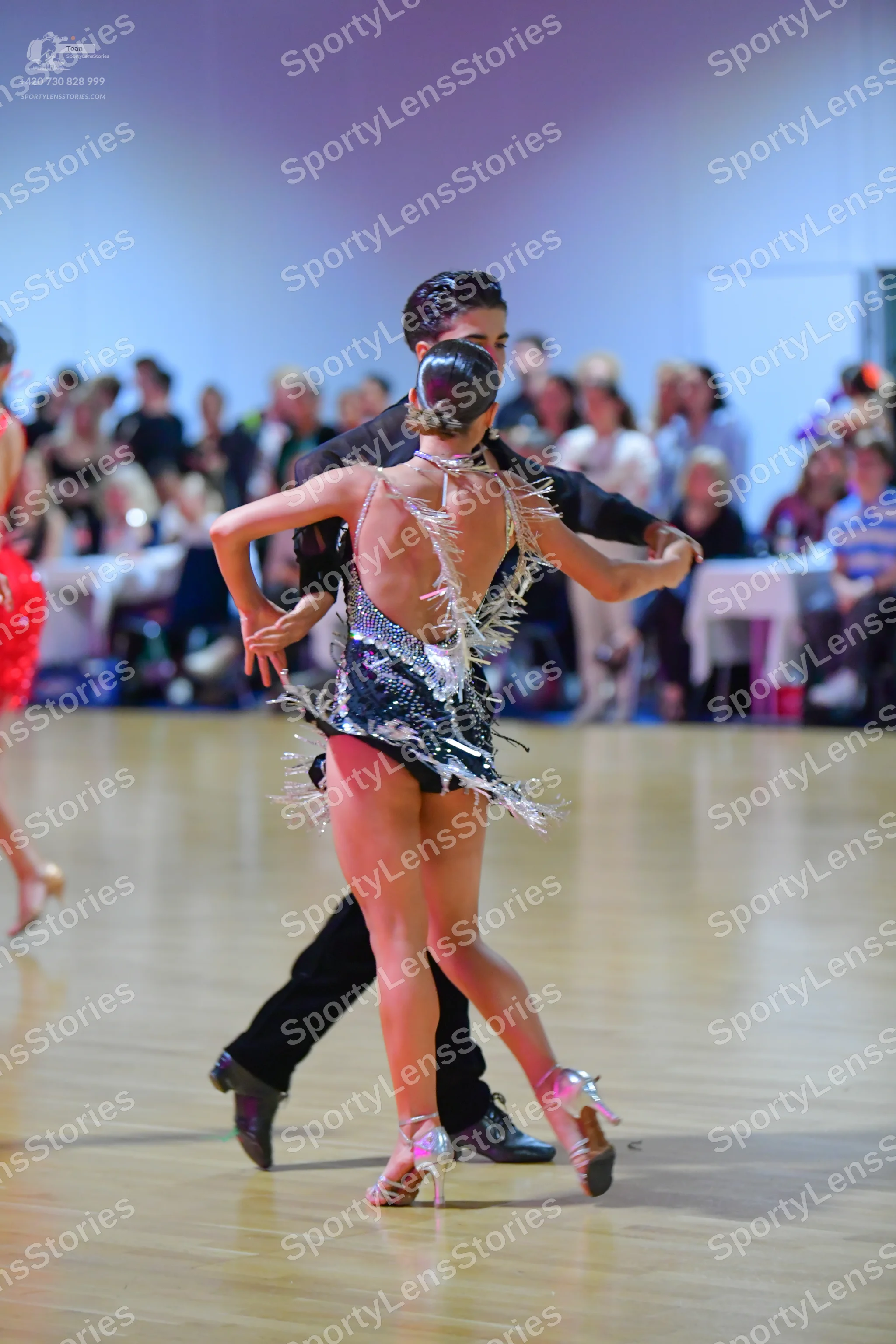 Dancesport competitor: Female dancer: black Latin dance outfit with silver/white shimmering fringe or s