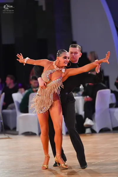 Dancesport competitor: Female dancer: gold sequined latin dress with fringe, gold strappy heels, and la