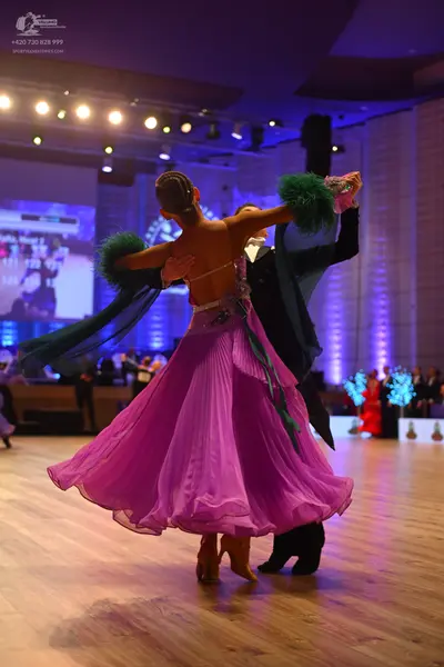 Dancesport competitor: Female dancer: pink ballroom gown with a full, flowing skirt and green/teal acce