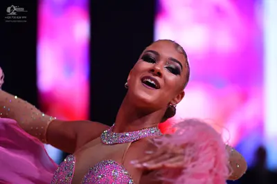 Dancesport competitor: Female dancer: pink and nude sequined latin dress with large pink feather-like e