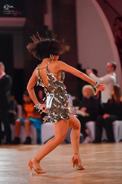 Dancesport competitor: Female dancer: black Latin dress adorned with large silver sequins or crystals, 