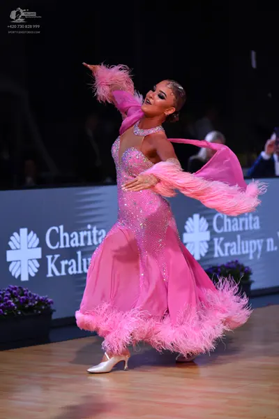 Dancesport competitor: Female dancer: bright pink latin dress with a sequin-covered bodice, sheer mesh 