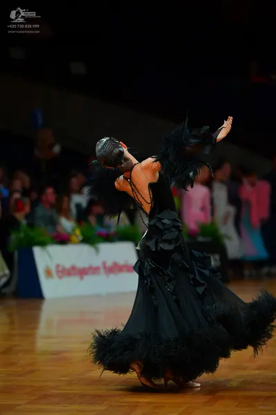Dancesport competitor: Female dancer: black ballgown with black feathers or ruffled fabric on the skirt