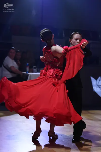 Dancesport competitor: Female dancer: red ballroom dress with a full, flowing skirt and red floral embe