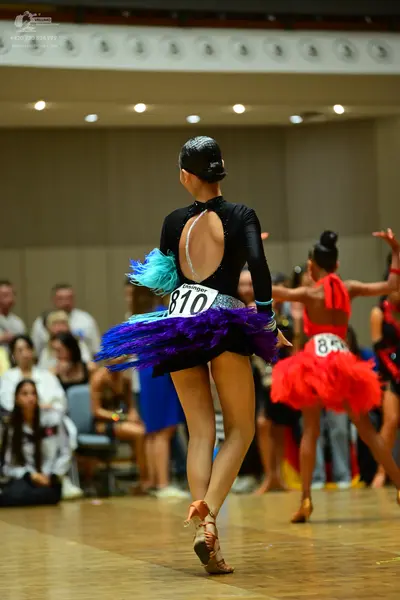 Dancesport competitor #810, #85: First dancer: black long-sleeved top with a keyhole back cutout and a multi-colo