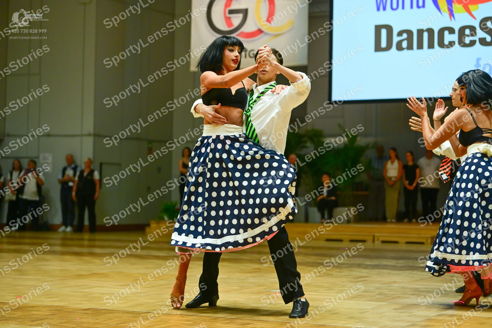 Dancesport competitor: Female dancer 1: black crop top and a white skirt with navy blue polka dots