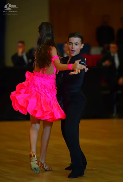 Dancesport competitor: Female dancer: bright pink latin dress with rhinestones and a ruffled skirt