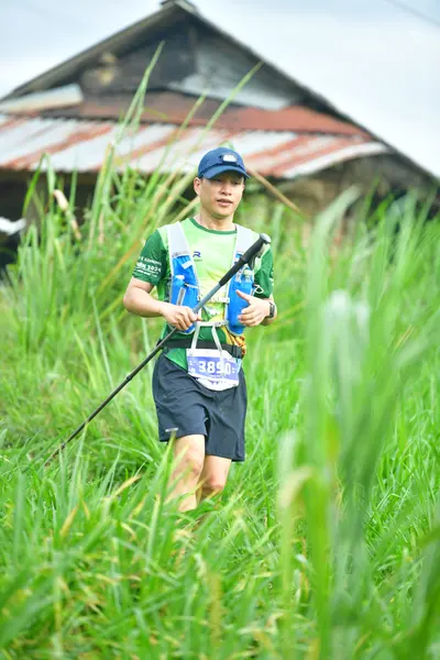 Marathon runner #385: Runner 1: green jersey, black shorts, blue cap, and a blue hydration vest